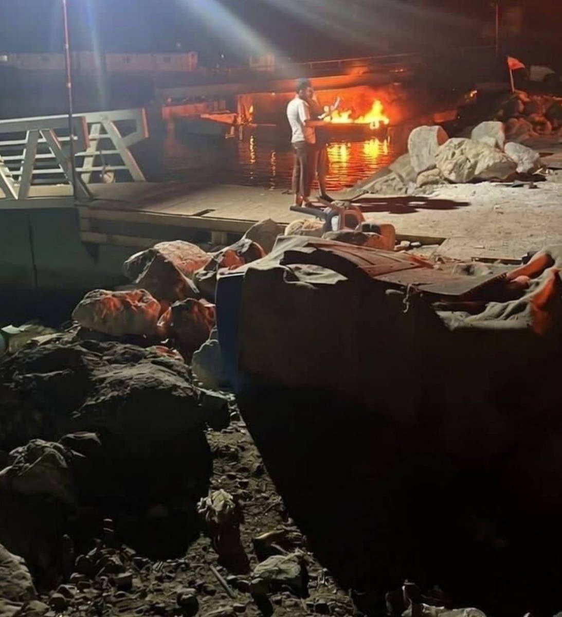 An OSINT account shared a photo of a burning boat at Shahid Haqqani Port in Bandar Abbas, Iran, following U.S. strikes, with geolocation at 27.17022, 56.26244.